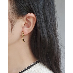 Elegant gold asymmetrical geometric drop earrings worn by a model in a modern style