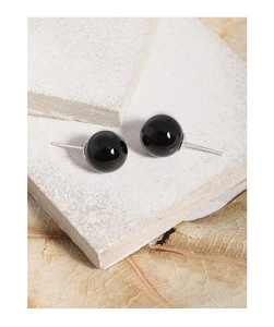 Detailed view of polished black agate ball earrings on natural stone and leaf background