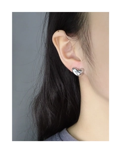 Close-up of minimalist S925 sterling silver heart stud earrings worn on a model's ear
