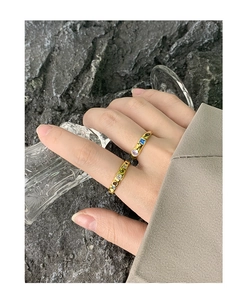 Detail of S925 silver gold-plated rings with colorful cubic zirconia on rock surface