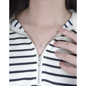 Minimalist silver geometric pendant necklace worn over a striped black and white sweater