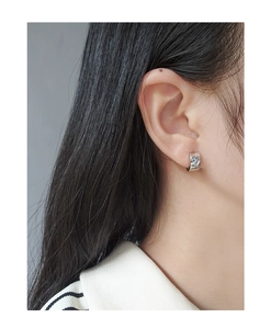Close-up of S925 silver wide huggie earring with heart shape and zircon on model ear