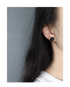 Close-up of minimalist black agate ball stud earring worn on a model's earlobe