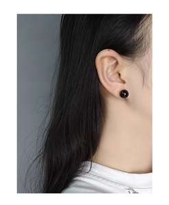 Close-up of a minimalist black agate sphere stud earring worn on a model's ear