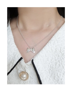 Detail of silver S925 bow pendant necklace with bead chain on model neck