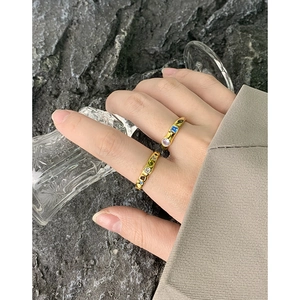 Golden textured S925 silver rings set with colorful zircons on a dark stone background