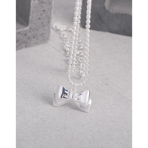 Polished S925 silver bow pendant necklace with round bead chain on a grey stone surface