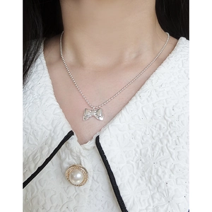 Elegant silver ball chain necklace featuring a polished bow pendant on a female neck