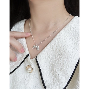Elegant S925 sterling silver beaded necklace with bow pendant on a model in white blouse