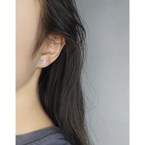Silver butterfly stud earrings with sparkling crystals worn by model in a close-up view