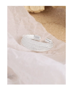 Macro detail of multilayer silver mesh wrap ring with textured finish on silk paper