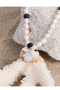 Détail du collier de perles et billes noires avec pendentif coquillage argenté
