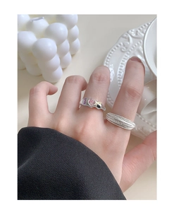 Detail of layered S925 silver rings set with colorful stones and textured wide band
