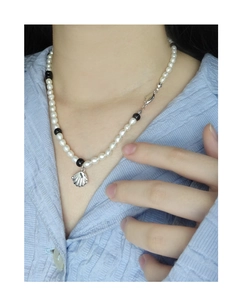 Gros plan du pendentif coquillage en argent S925 sur collier en perles et perles noires