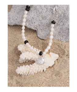 Vue détaillée du pendentif coquillage avec perles et perles noires sur corail blanc