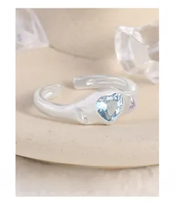 Vue macro d'une bague coeur en argent avec gemme bleue et pierres de zircon colorées