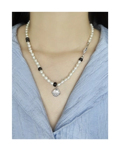 Détail du pendentif en coquillage sur collier de perles naturelles sur un modèle