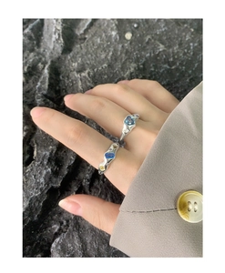 Unregelmäßig flüssiges Ringdesign mit blauem Zirkon, am Modell mit grauem Anzug