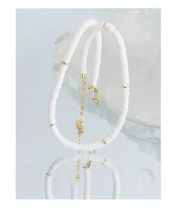 Détail du collier en perles de céramique blanche avec fermoir mousqueton doré
