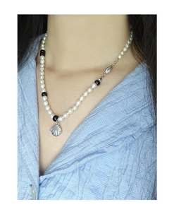 Détail d'un pendentif coquillage en argent S925 sur collier en perles blanches et noires