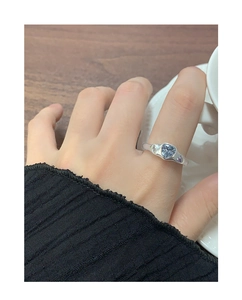 Gros plan bague en argent avec pierre bleue en cœur et zircons sertis sur la main