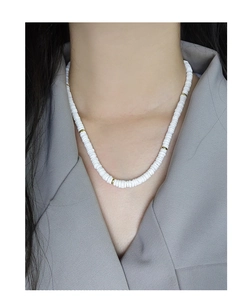 Détail du collier en perles heishi de céramique blanche avec perles doreés sur modèle
