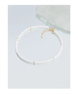 Détail du collier de perles en céramique blanche avec perles dorées et fermoir mousqueton