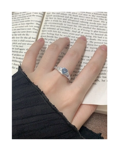 Détail d'une bague coeur en zircon bleu sur anneau large argenté avec manche noire