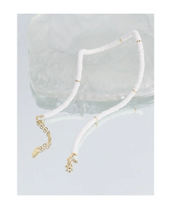 Détail d'un collier en perles Heishi blanches en céramique avec fermoir doré