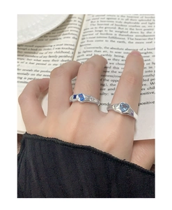 Détail des bagues en argent S925 avec zircon bleu en forme de cœur et texture fluide