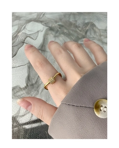 Detail view of a gold curved triple zircon ring worn by a model with a gray suit