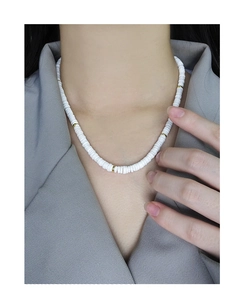 Détail de perles en céramique blanche et perles plates dorées sur collier en argent S925