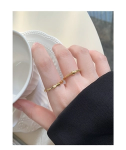 Detail of gold bamboo-textured rings and cube bead band worn in elegant setting
