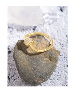 Close-up of a gold U-shaped ring featuring a sparkling pavé zircon slider on a stone base
