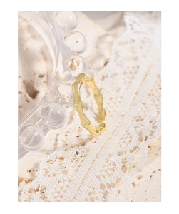 Detailed view of an adjustable gold bamboo joint ring on elegant lace and stone backdrop