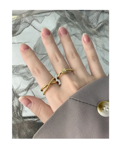 Detailed close-up of layered gold rings with zircon accents on a gray suit background