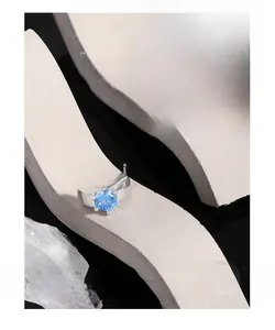 Dettaglio di orecchini in argento con zirconi blu tondi su supporti in pietra grigia