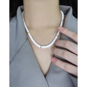 Collier en argent S925 et céramique blanche avec perles dorées porté sur un blazer