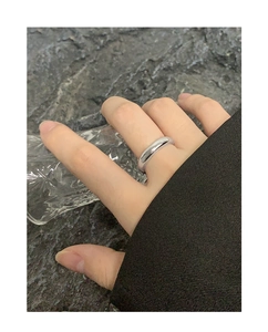 Close-up of a minimalist silver polished ring worn on hand with a glass background