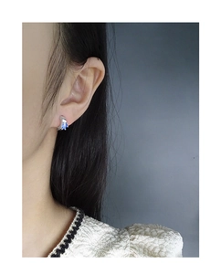 Dettaglio ravvicinato di orecchino in argento S925 con zircone blu indossato da modella