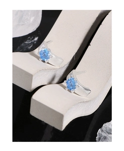 Dettaglio di orecchini con zircone blu e castone a sei griffe su supporto artistico