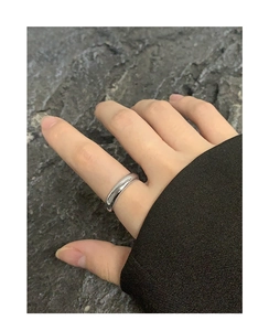 Close-up of minimalist chunky silver ring on finger against stone background