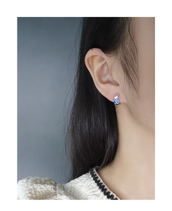 Orecchino a cerchio argentato con zircone blu brillante indossato da una modella
