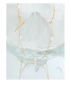 Macro detail of minimalist gold S925 silver necklace with white pearls and logo tag