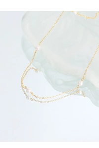 Detailed view of minimalist gold pearl necklace with polished beads on ice block background