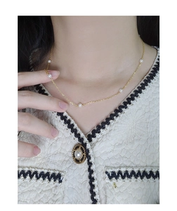 Detailed view of elegant gold pearl necklace on model in luxury tweed jacket outfit