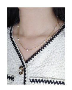 Close-up of minimalist gold pearl necklace on model with white tweed jacket