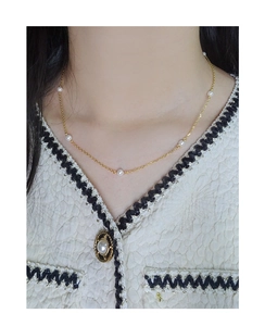 Detailed view of elegant gold pearl necklace on model with tweed jacket collar