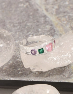 Detail of silver S925 ring with irregular texture and colorful zircon heart gemstones