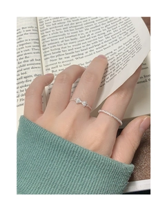 Detail von silbernem S925 Schleifenring-Set mit Zirkonia am Finger und Buchhintergrund